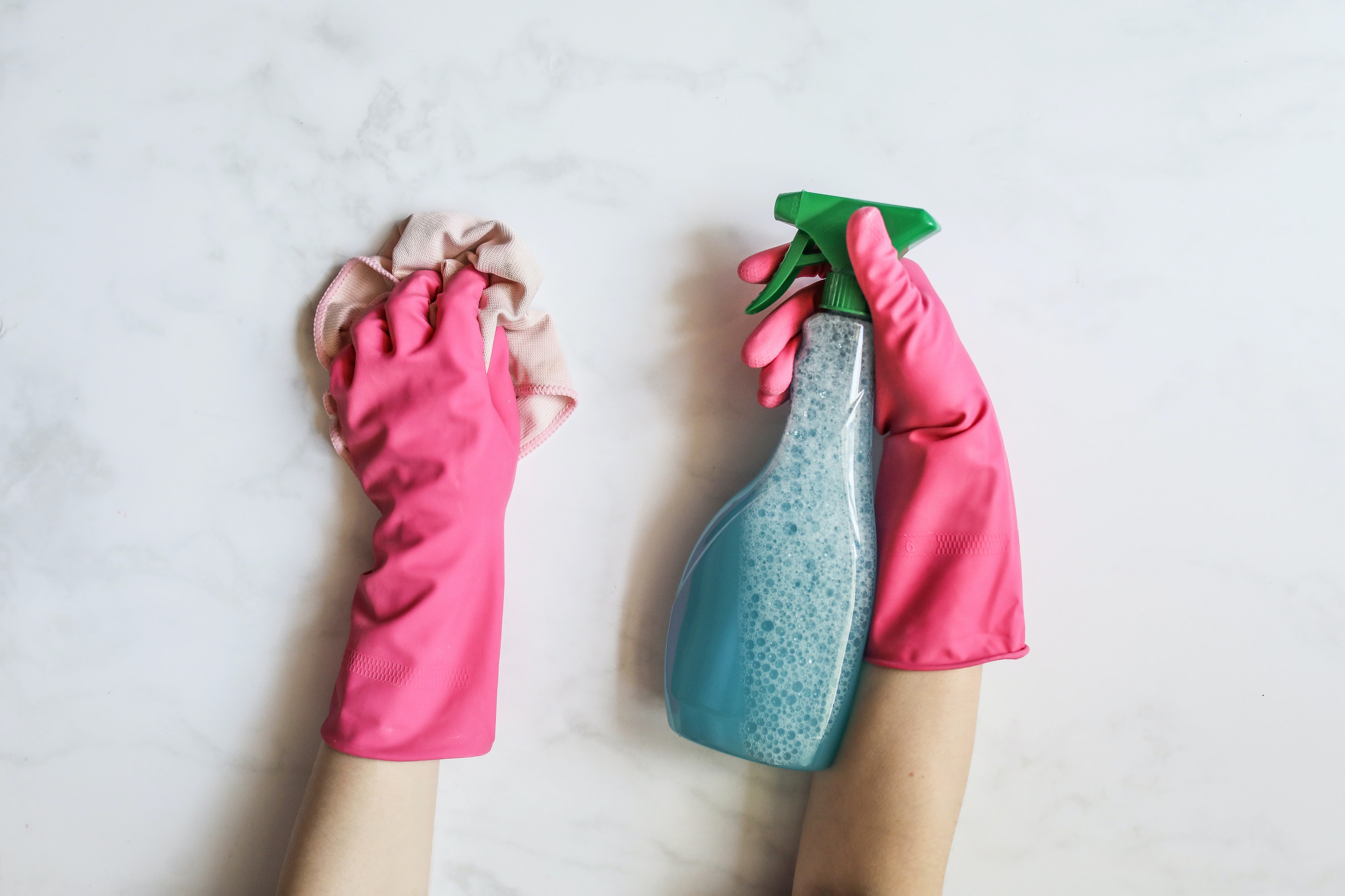Pink cleaning gloves with a blue bottle and rag